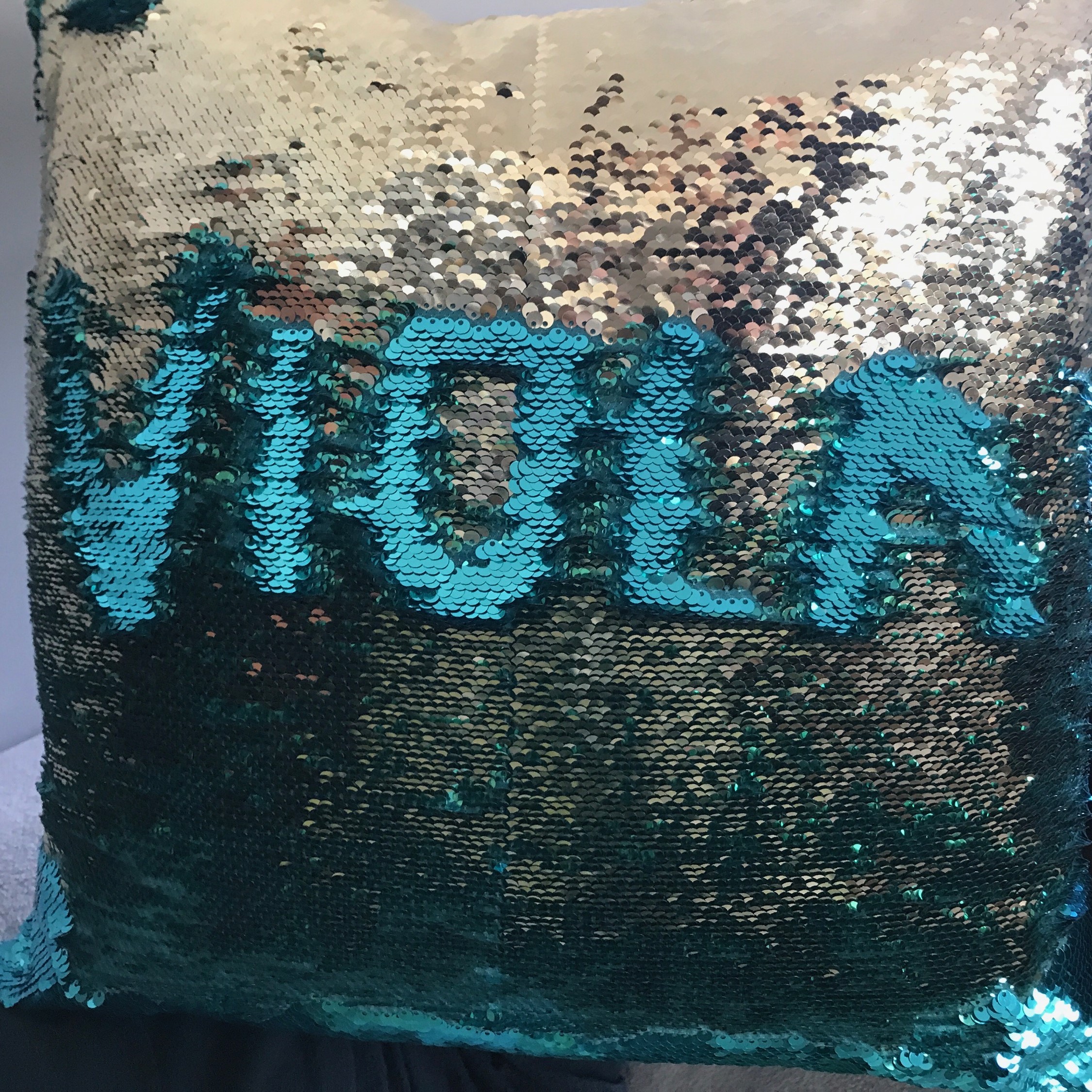 A pillow with sequins arranged to spell ``viola``.